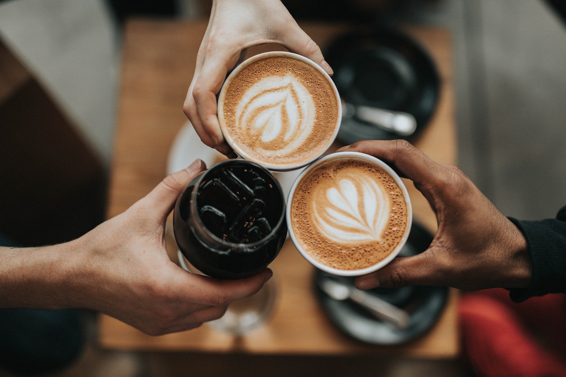 Three hands holding coffee cups, enjoying coffee from pawsomecoffee